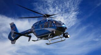 A blue police helicopter patrolling the sky on a clear sunny day.