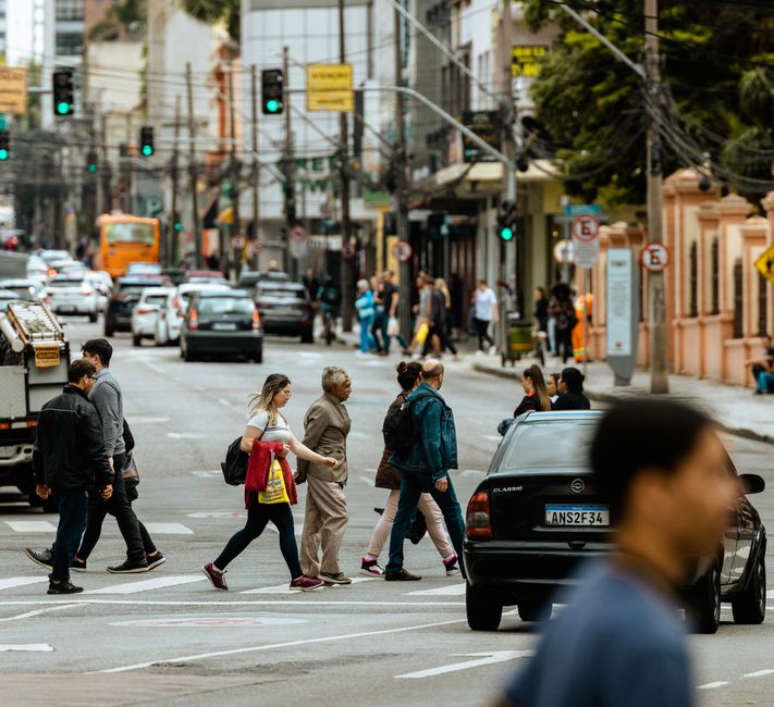 A bustling urban crosswalk with pedestrians and traffic during the day.