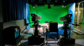 A TV studio setup featuring cameras and a green screen for production purposes.