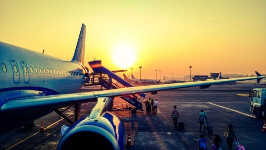 A vibrant image of passengers boarding an airplane at sunrise, highlighting air travel.