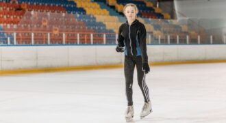 A young woman glides gracefully on an indoor ice rink, showcasing her skating skills.