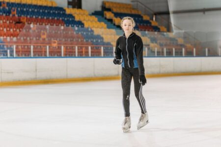 A young woman glides gracefully on an indoor ice rink, showcasing her skating skills.