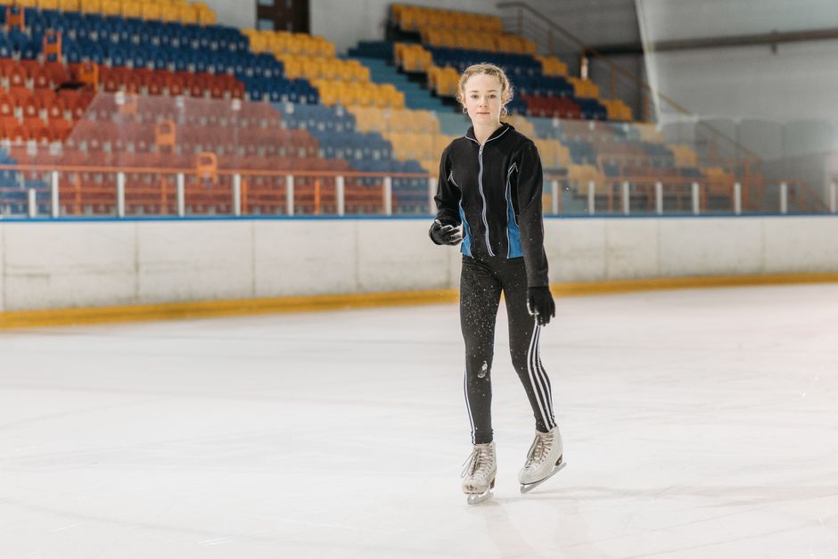 A young woman glides gracefully on an indoor ice rink, showcasing her skating skills.