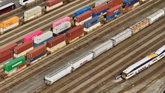 Aerial shot showcasing colorful freight containers on train tracks in a busy transportation yard.