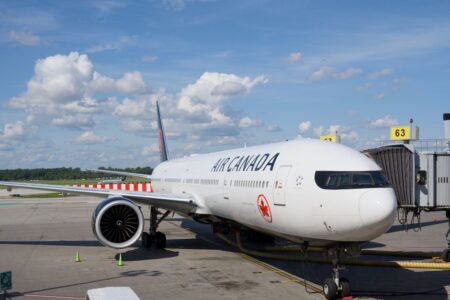 Air Canada Boeing 777 airplane parked at an airport gate under a clear blue sky.