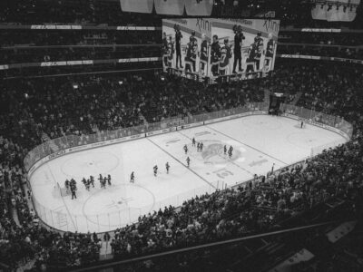 Black and white overhead shot of a thrilling ice hockey game with a full audience in an indoor arena.