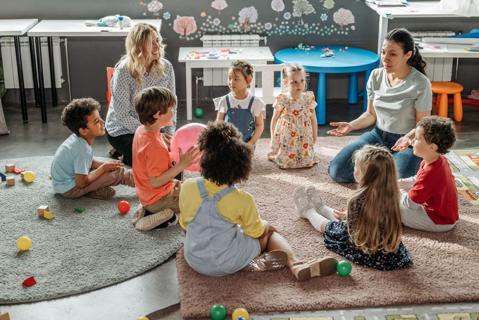 Children in circle time with teachers, engaging in a kindergarten classroom activity.