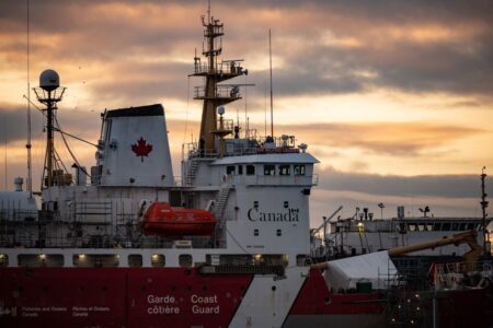 Close-up of a Canadian Coast Guard ship docked at sunset, showcasing maritime details.