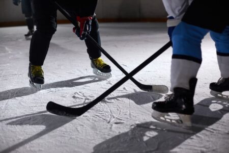 Close-up of hockey players battling for puck during an intense face-off on a lighted ice rink.