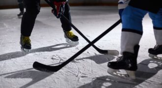 Close-up of hockey players battling for puck during an intense face-off on a lighted ice rink.