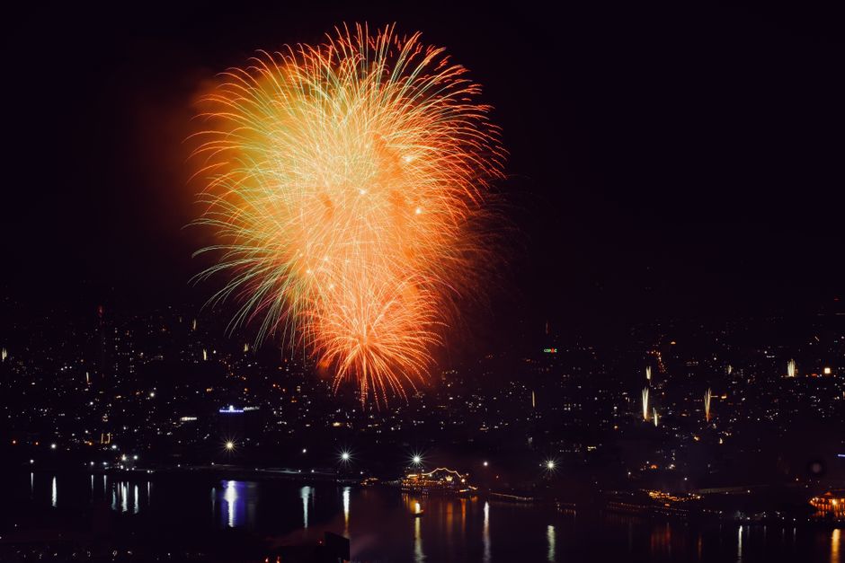 Colorful fireworks illuminate the cityscape at night, creating a festive and vibrant atmosphere.
