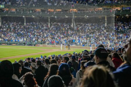 Energetic scene of a nighttime baseball game with a packed stadium crowd.