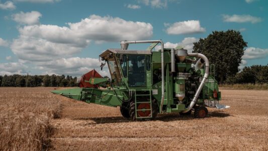 Green combine harvester operating in a wheat field in Hohenhorn, Germany under a clear blue sky.