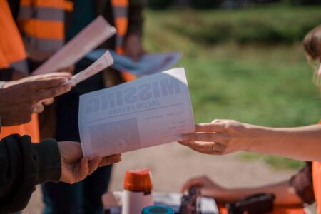 Group of volunteers handing out missing person flyers during a search operation outdoors.