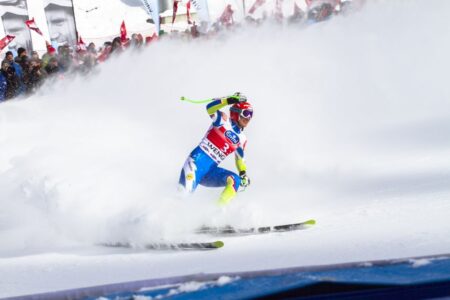Intense ski race action captured with athlete carving through snowy slope in winter.