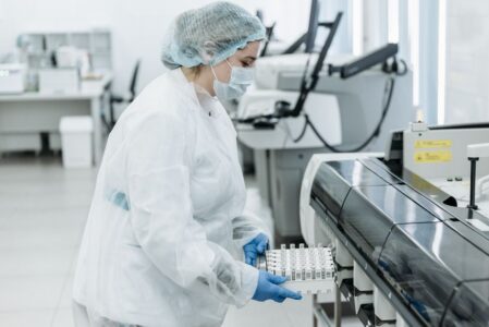 Laboratory scientist in protective gear working with medical samples.