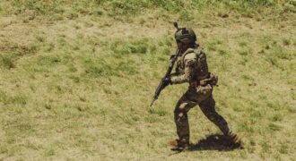 Military soldier in tactical gear running during training exercise at Campo de Mayo, Argentina.