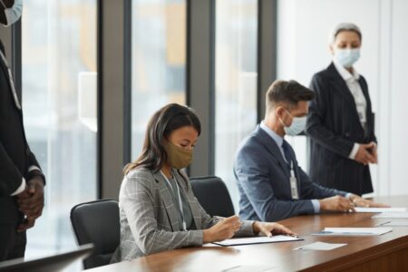 Professionals in face masks having a business meeting in a modern conference room.