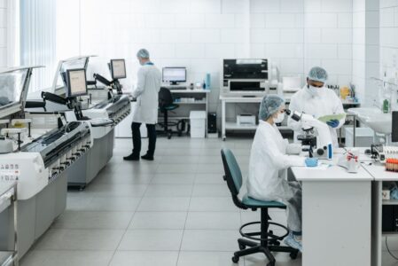 Researchers in lab coats performing experiments with advanced equipment in a laboratory.