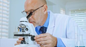 Scientist examining samples through a microscope in a modern laboratory setting.