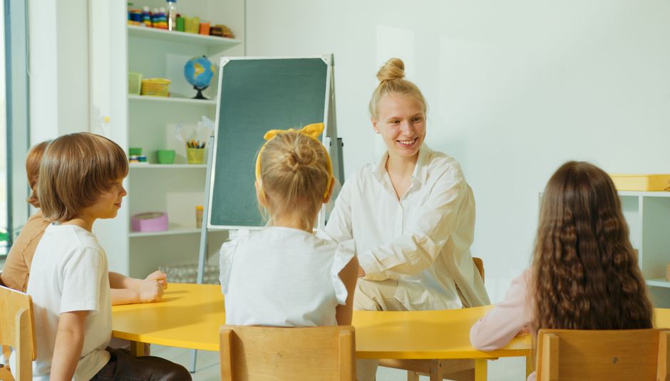Teacher engaging with preschool children in a colorful classroom setting.